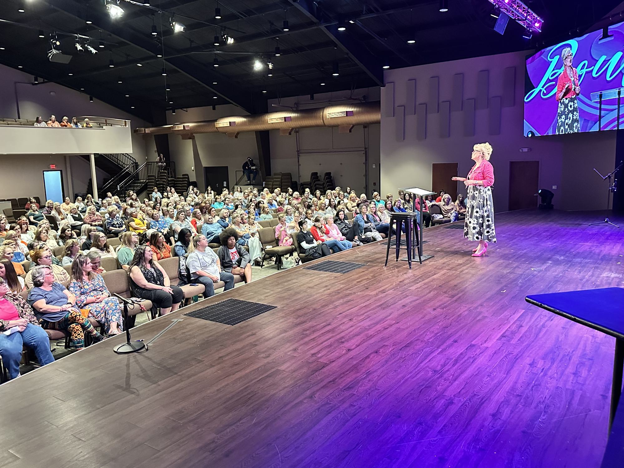 Robyn Dykstra speaking on stage to a full room of women